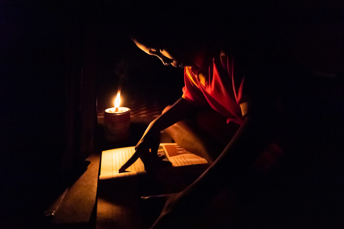 A young boy reads by candlelight at his home in Phang-nga, Thailand, which does not have electricity, December 8, 2021. He is a member of the Moklen, an ethnic group living along the Andaman Coast in Southern Thailand with its own language that lacks an alphabet. A team of linguists and anthropologists are working together with local communities to document and revitalize Moklen language and culture as an empowering tool to enhance cultural assets and strengthen identity of this marginalized ethnic group.