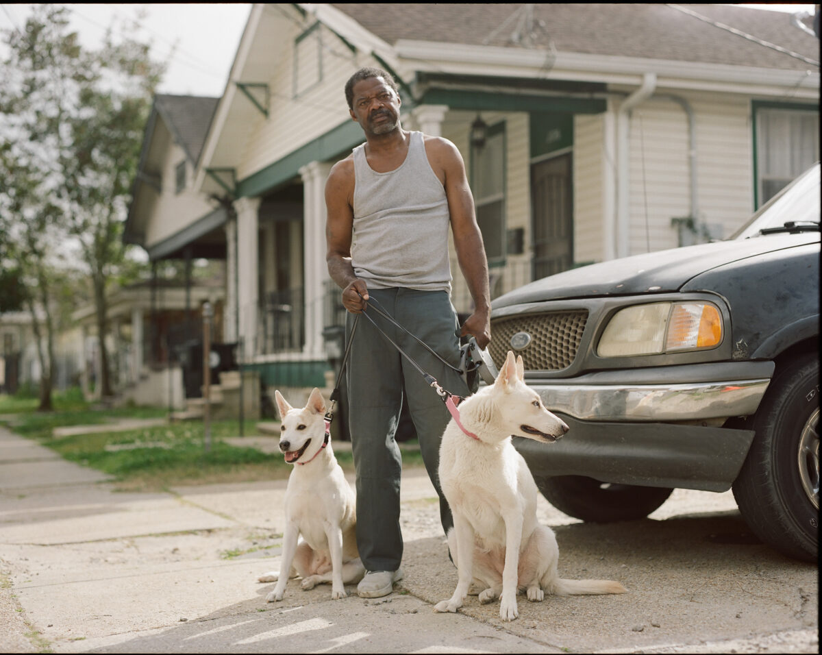 DeRay stands outside with his dogs in New Orleans, March 12, 2022. He tells the photographer that these pups were actually his daughter’s that he takes care of.