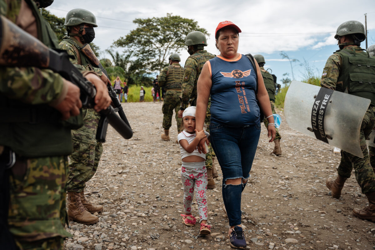A woman and child walk past the riot police during a protest against state-owned oil company Petroecuador, which maintains its oil extraction field next to Lago Agrio, Ecuador May 3, 2022.