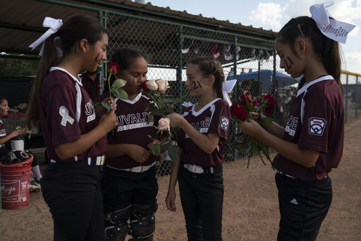 Ten-year-olds Aubrey Gómez, Callie Sánchez, Gina Gatto, and Gabriela Jiménez smell the roses that were given to them before the game in honor of the victims of the mass shooting that resulted in the death of 19 children and two teachers in Uvalde, Texas on June 18, 2022. The girls said they knew some of the victims of the mass shooting.