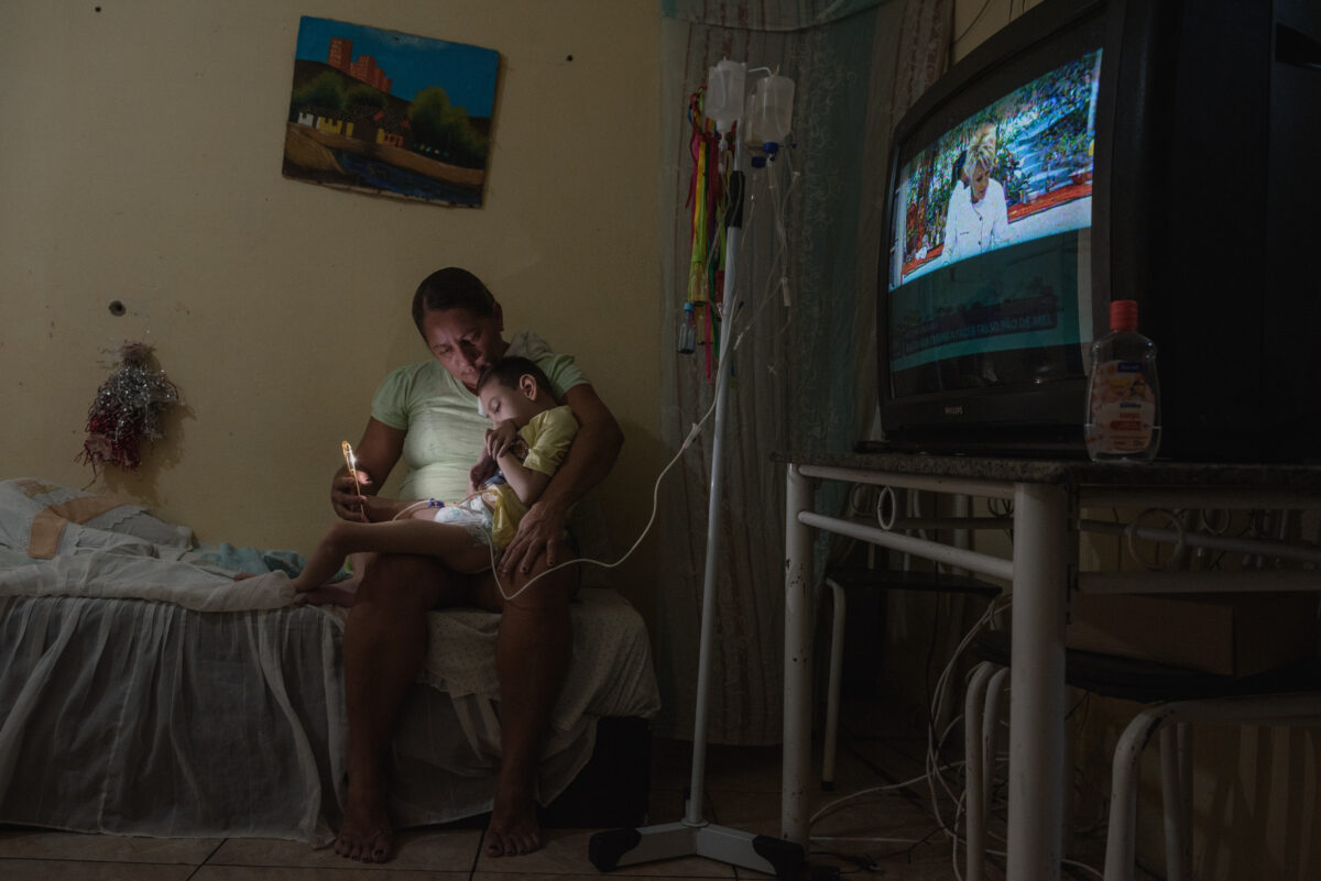 Josimary Gomes feeds her son Gilberto, 6, through a gastric tube in Algodão de Jandaíra, Paraíba, Brazil, February, 17, 2022.. Gilberto has low vision and enjoys looking at lights so she uses a cell phone to calm him down. Gilberto and more than 4,000 children were born with microcephaly in Brazil between 2015 and 2016, due to the Zika virus outbreak transmitted by the mosquito.