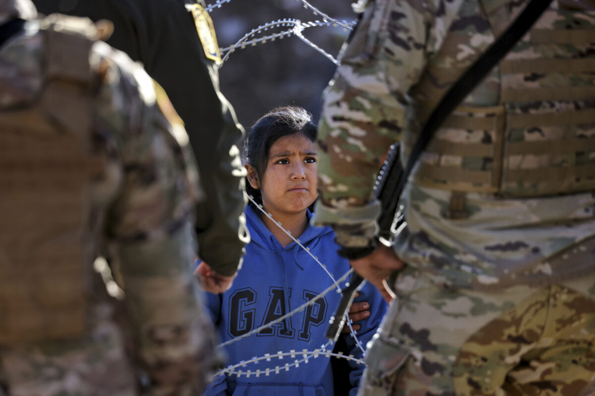 Children watch as members of the Texas National Guard stop a group of asylum-seeking migrants, that the children are a part of, from crossing the border into the United States in El Paso, Texas, U.S., December 21, 2022. REUTERS/Jim Urquhart for NPR